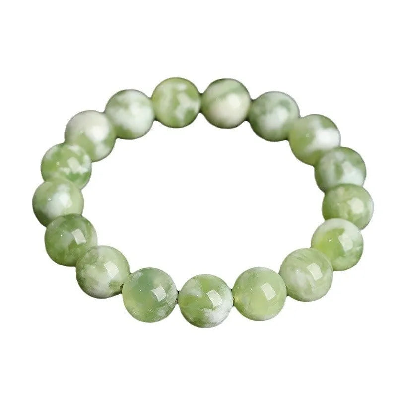 Green milk-in-water Xiuyan jade bracelet with polished geometric beads on a wrist.