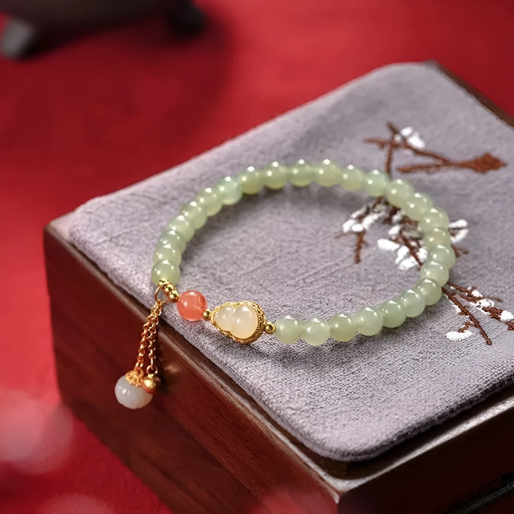 Qingshui jade women's bracelet with gold plated beads and a fu character charm.