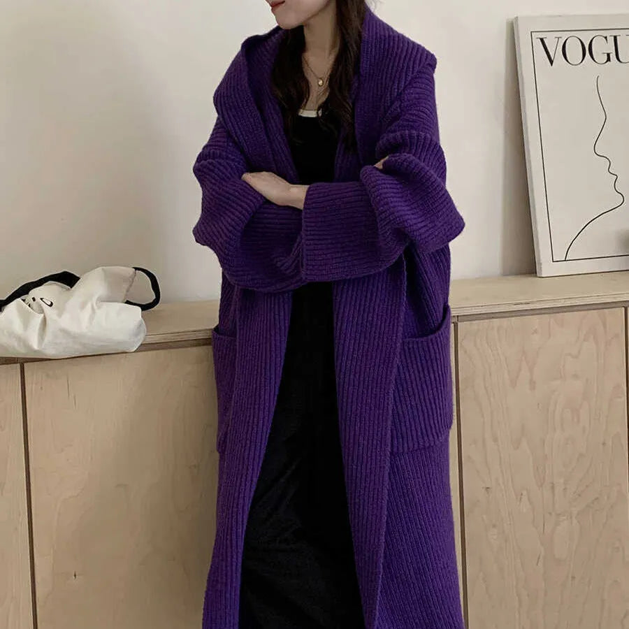 Woman wearing a longline loose grey hooded cardigan coat with raglan sleeves.
