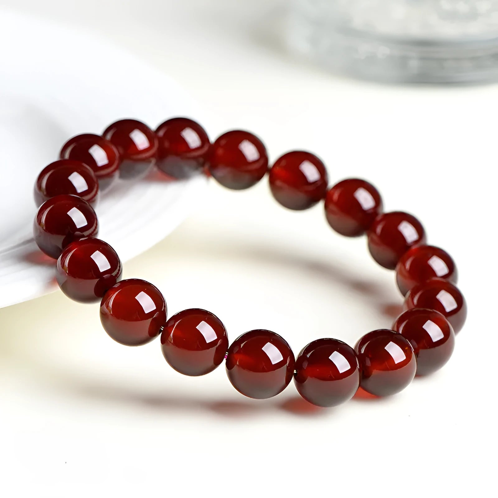 Natural orange red garnet ball bracelet with a silver Ruyi charm on a white background.