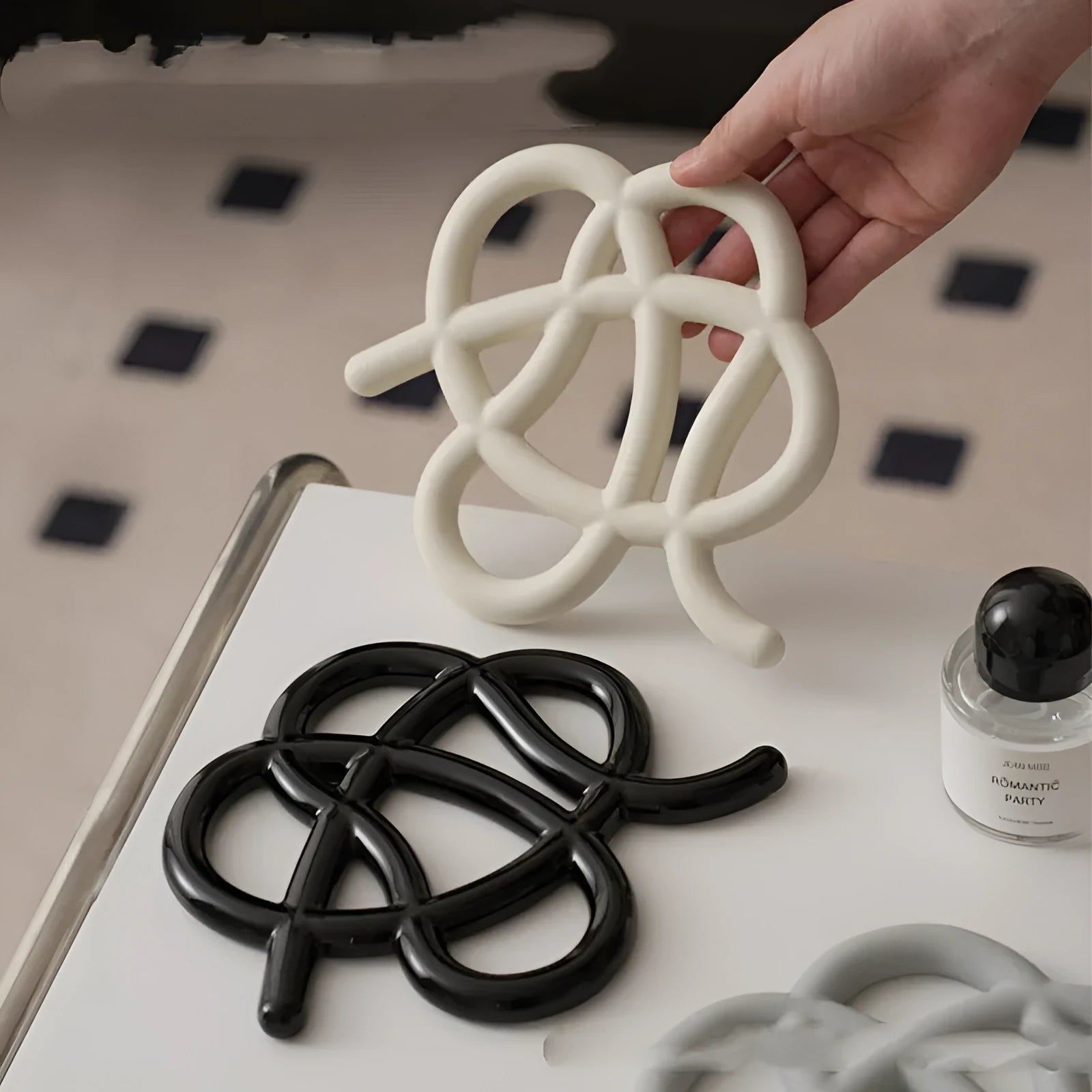 Irregular-shaped ceramic heatproof mat in a solid colour on a wooden table, protecting it from a hot pan.