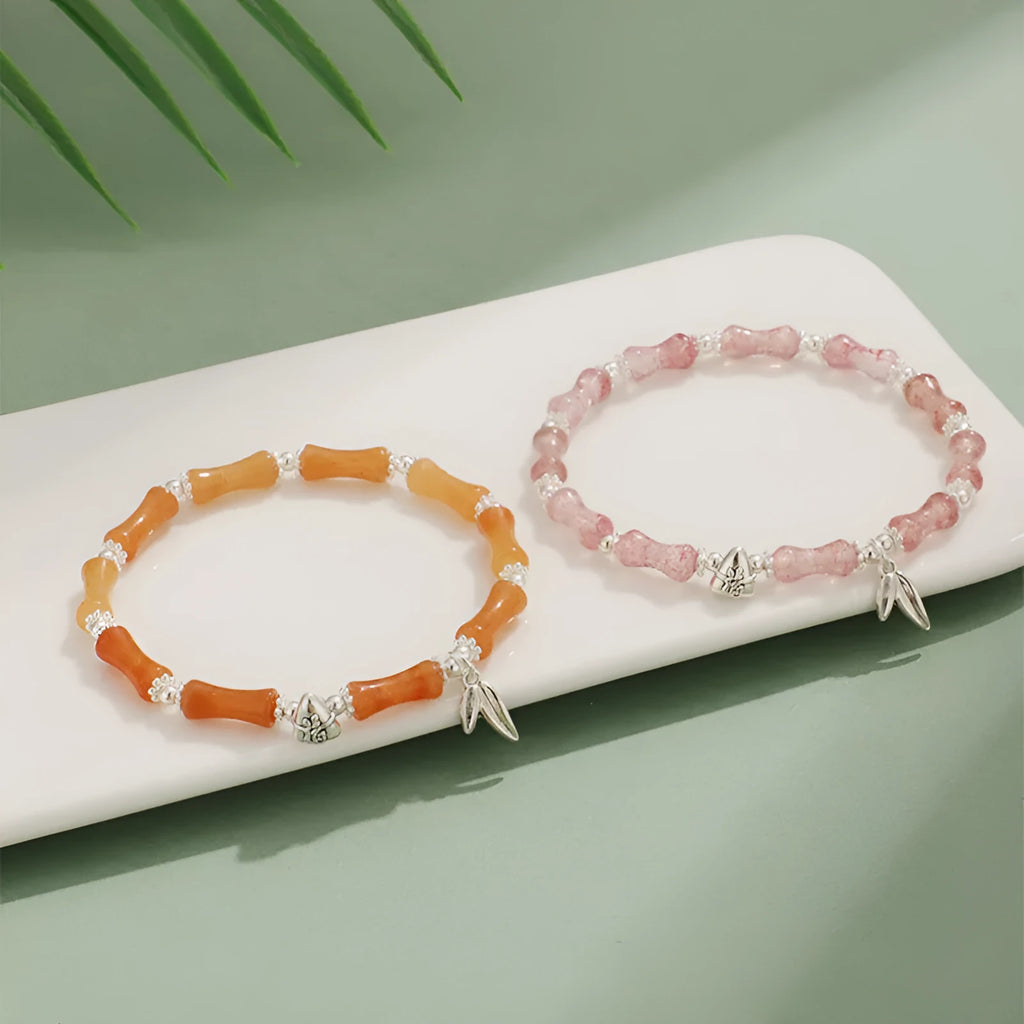 Women's green aventurine crystal bracelet with bamboo, strawberry quartz, and jade beads on wrist.
