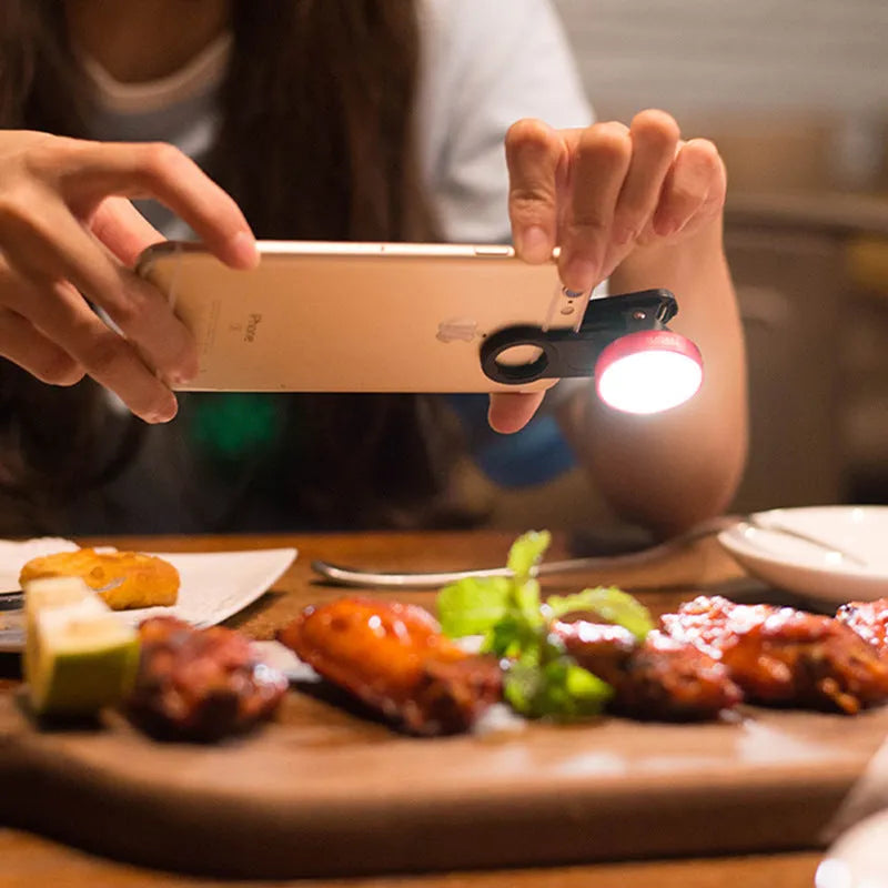 Smartphone wide-angle camera lens attachment with LED light ring in black, red, and silver grey colours.