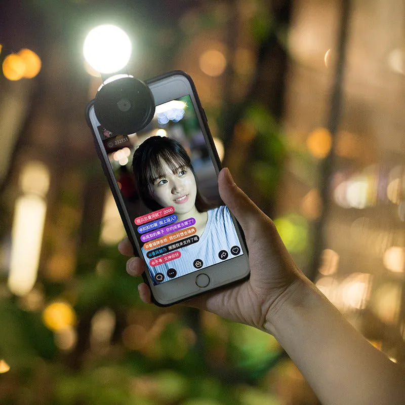 Smartphone wide-angle camera lens attachment with LED light ring in black, red, and silver grey colours.