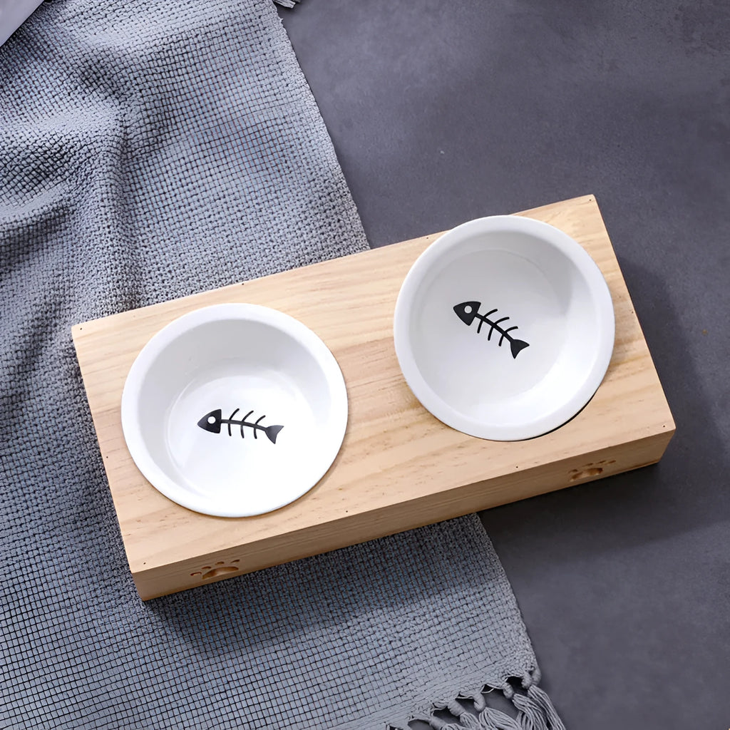 Solid wood pet feeding table with stainless steel bowls in a raised design for cats.