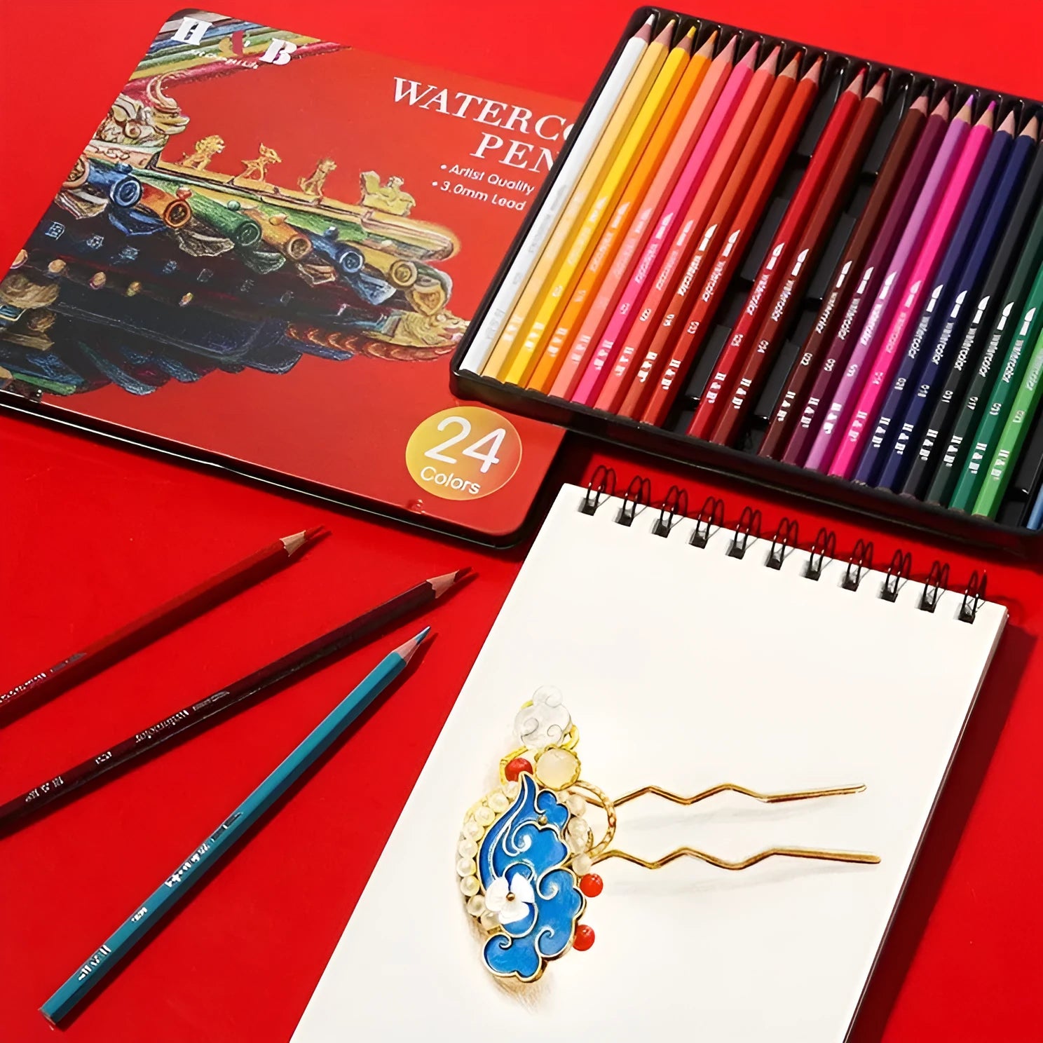 Water-soluble coloured pencil set with brush in an open iron storage tin, showing 24 wooden pencils.