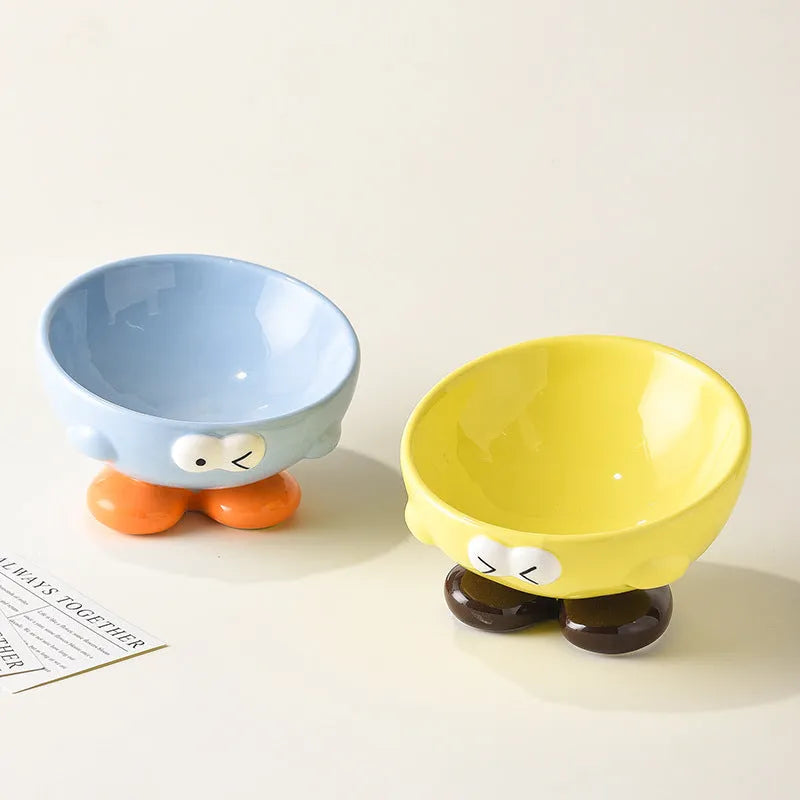 Blue ceramic pet bowl with tall, angled sides and a cute face design for cat or small dog feeding.