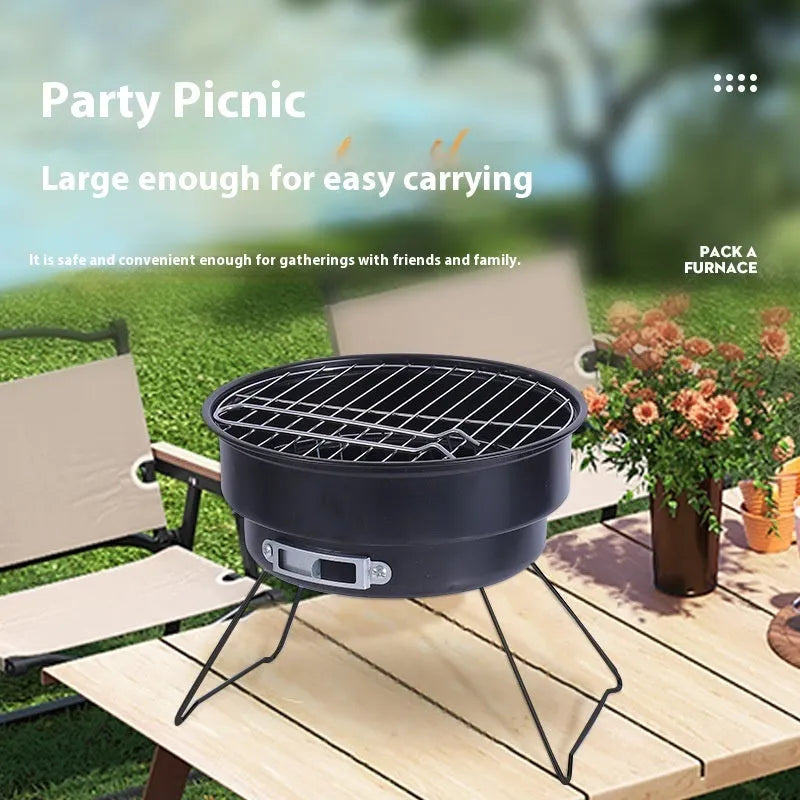 Small round folding metal barbecue stove with grill and storage bag, set up for outdoor cooking.