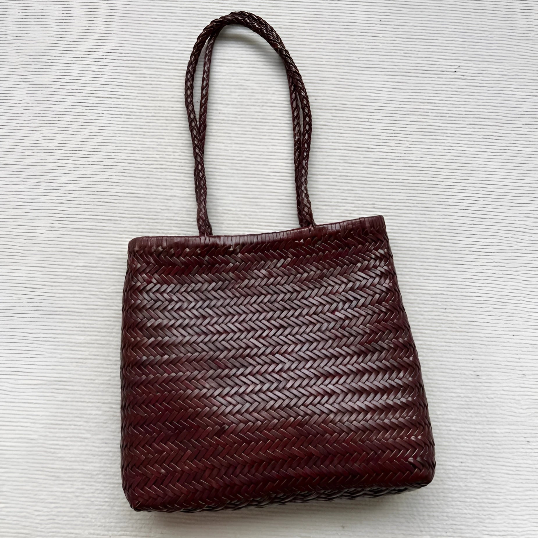 Brown handmade woven cowhide leather tote bag with a three-dimensional outer pocket.