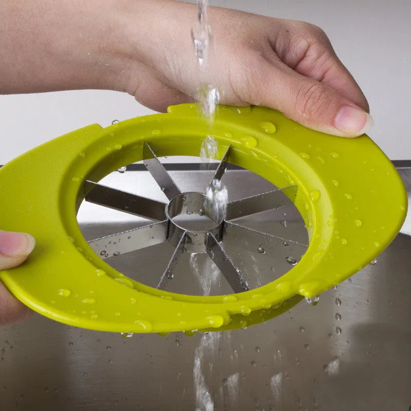 Green plastic fruit slicer for apple, tomato and mango cuts with base on a kitchen counter
