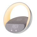 Beige multifunctional Bluetooth speaker with wireless charging surface and ambient LED lighting on bedside table