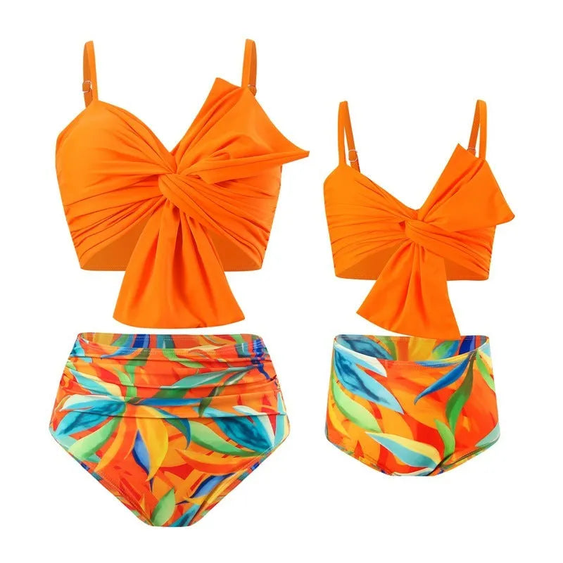 Women's big bow bikini and swim trunks set in a colourful print, shown in orange colour.