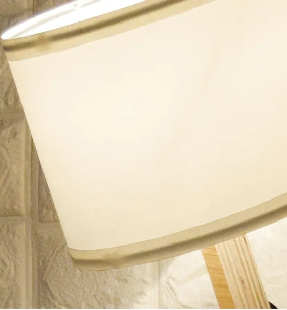 Creative humanoid wooden table lamp with white fabric shade and deformable design on a wooden surface
