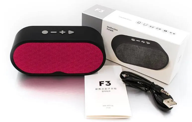 Grey portable Bluetooth speaker with TF card slot, USB port, and built-in microphone on a table.