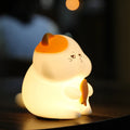 Yellow Greedy Cat cartoon desktop night light with USB cable on a wooden desk.