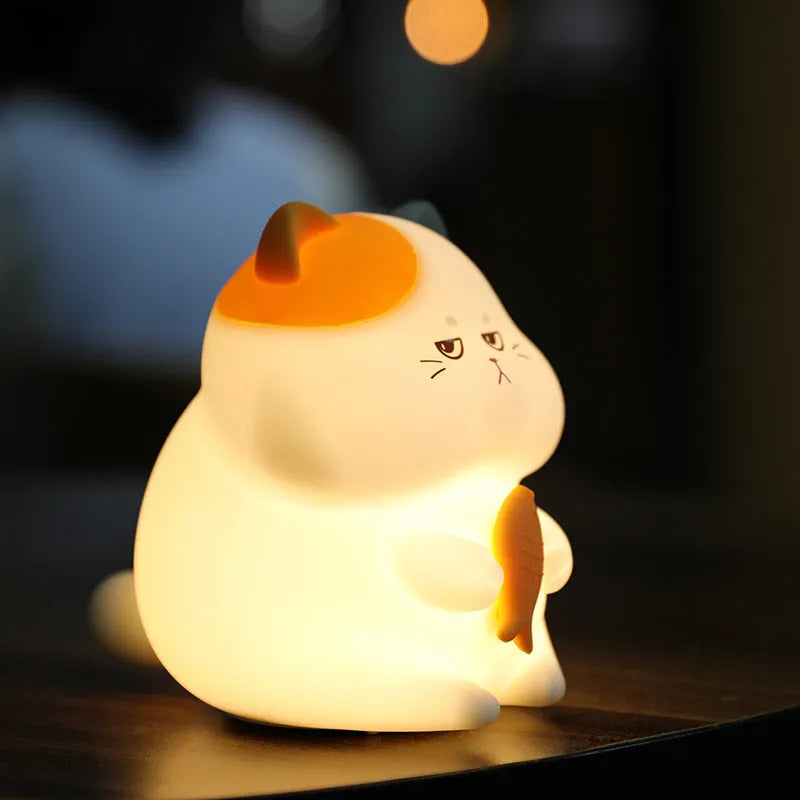 Yellow Greedy Cat cartoon desktop night light with USB cable on a wooden desk.