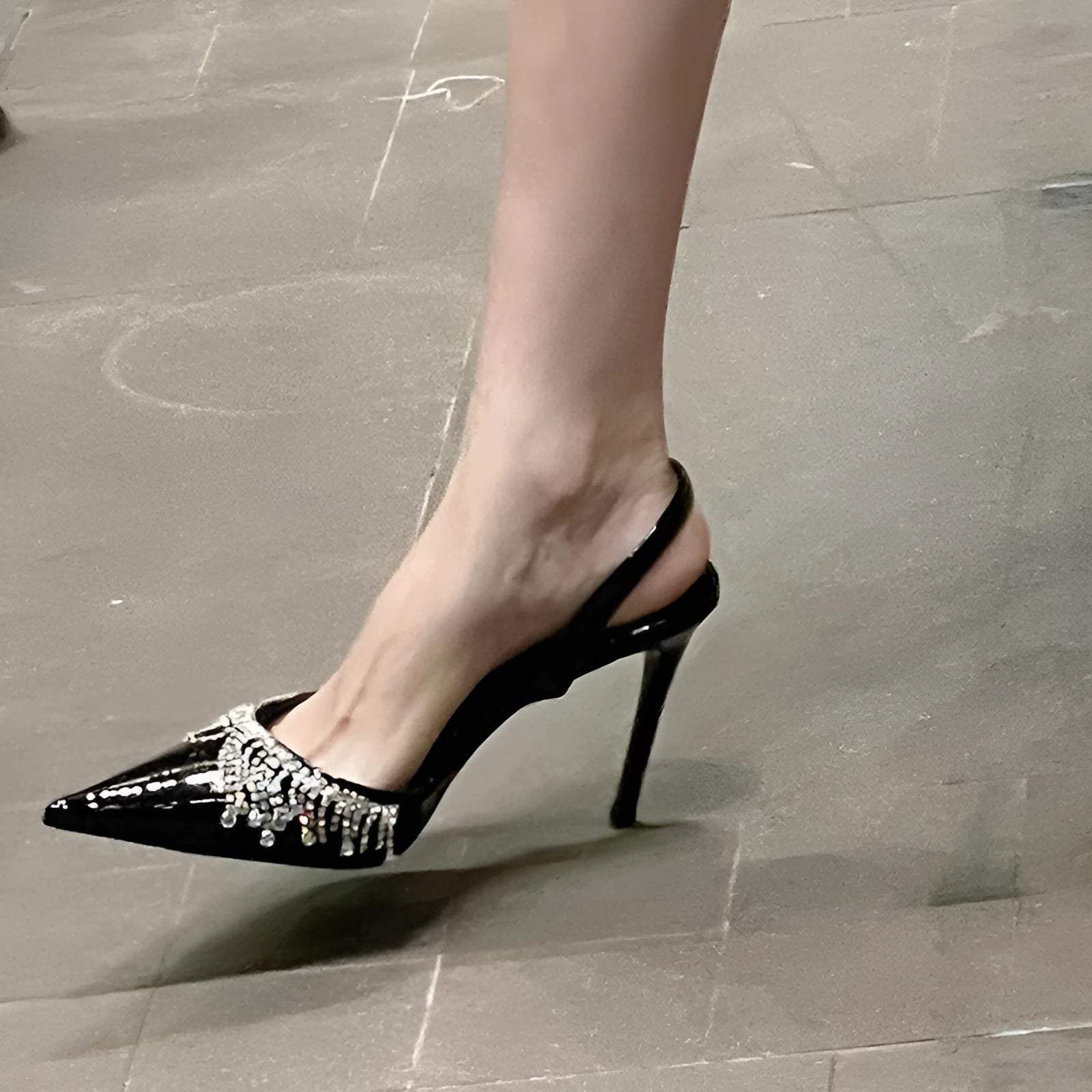 Black high heel sandals with rhinestone tassel decoration, pointed toe, and slingback strap showing 10cm stiletto heel