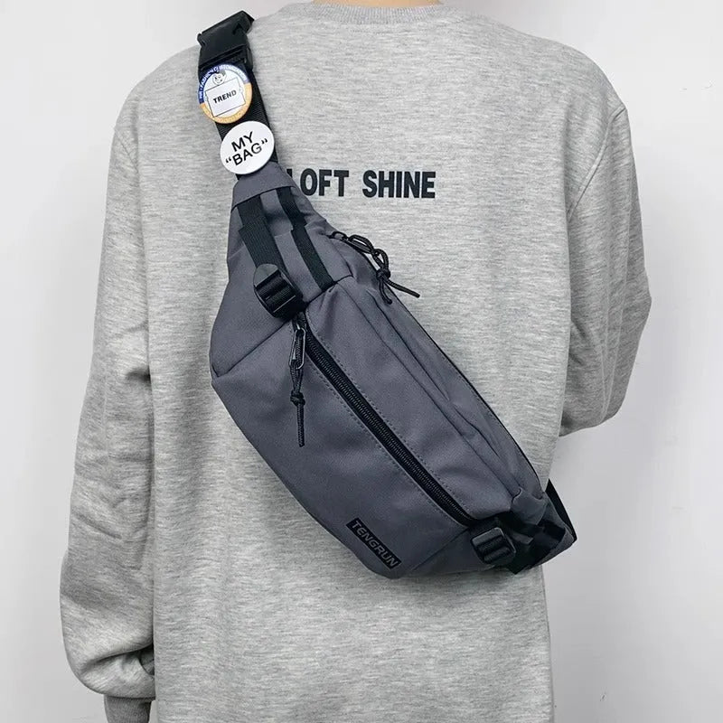Trendy chest bag for men in Oxford cloth with letter pattern, adjustable strap, and two random badges on a plain background