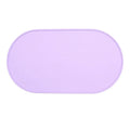 Beige silicone cat feeding mat with raised edge containing a food bowl and scattered kibble on a kitchen floor.