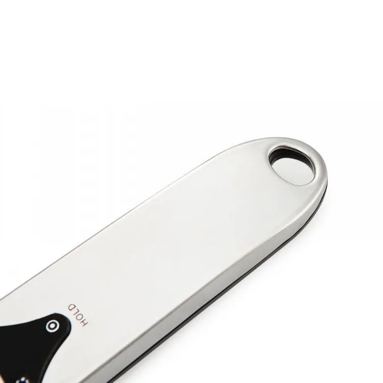 Digital smart measuring spoon with electronic display showing weight, placed on a kitchen worktop.