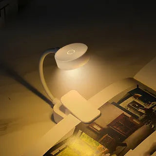 Portable rechargeable clip light in modern simplicity style clipped onto a desk for reading