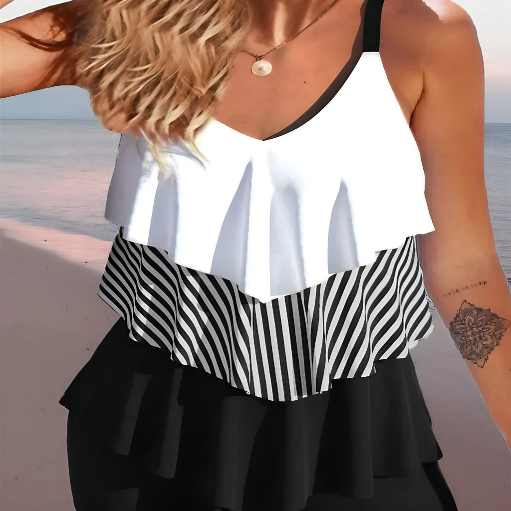 Women's sleeveless backless bikini swimsuit with spaghetti straps and ruffle detail on a solid colour background.