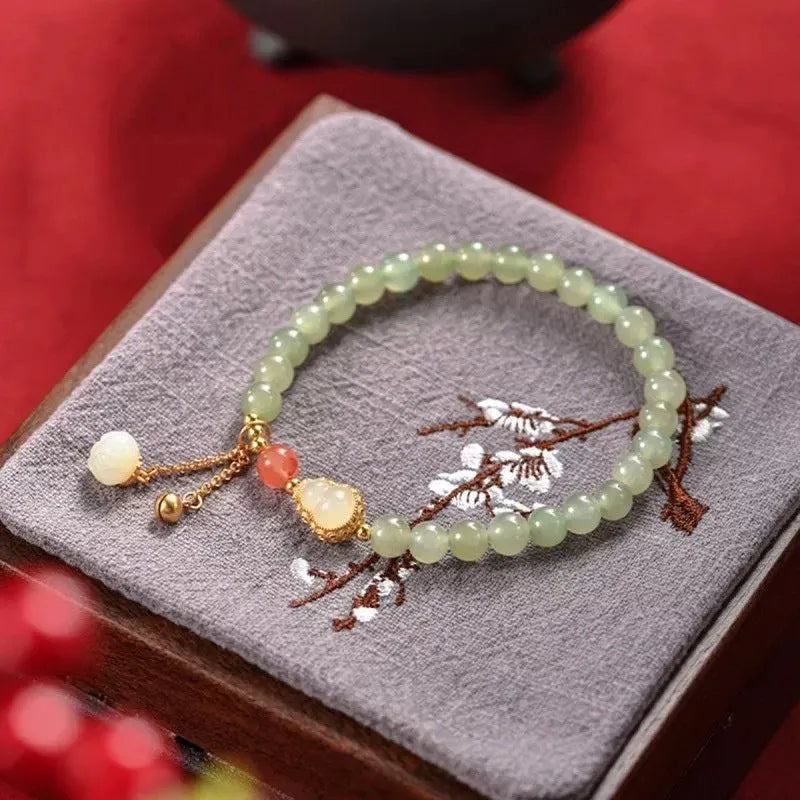 Qingshui jade women's bracelet with gold plated beads and a fu character charm.