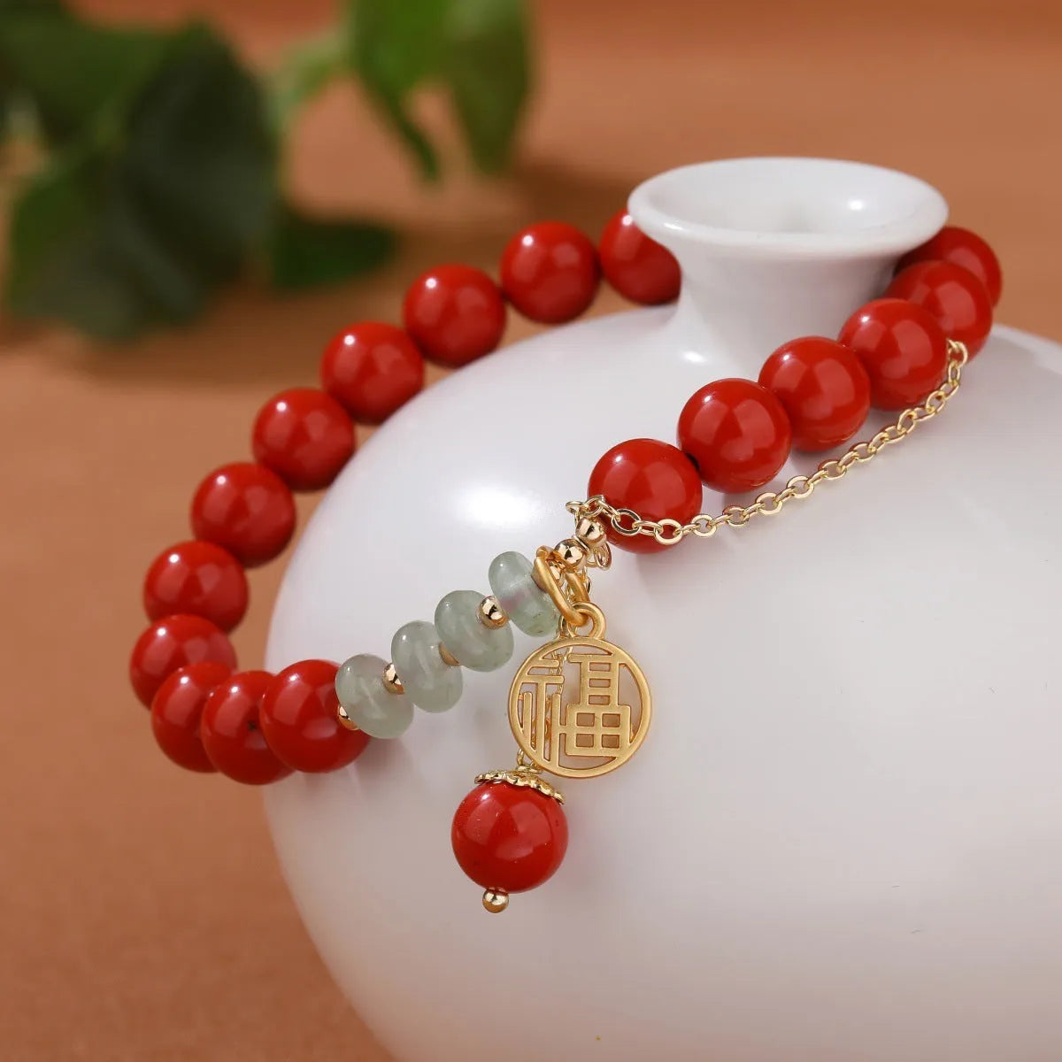 Women's red cinnabar bracelet with fu character charm, jade spacer bead, and tassel design