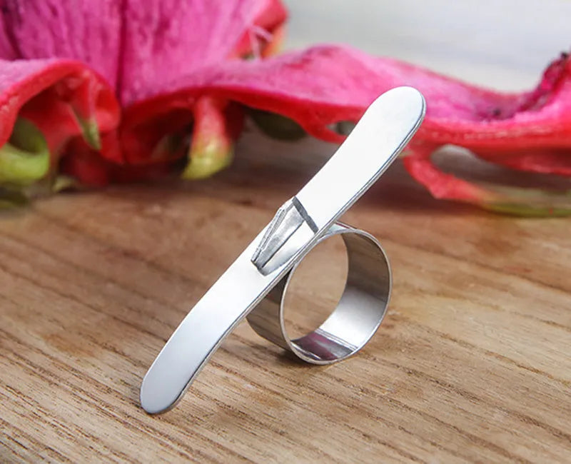 Silver stainless steel kitchen peeler tool with a finger ring for peeling oranges and citrus fruit.