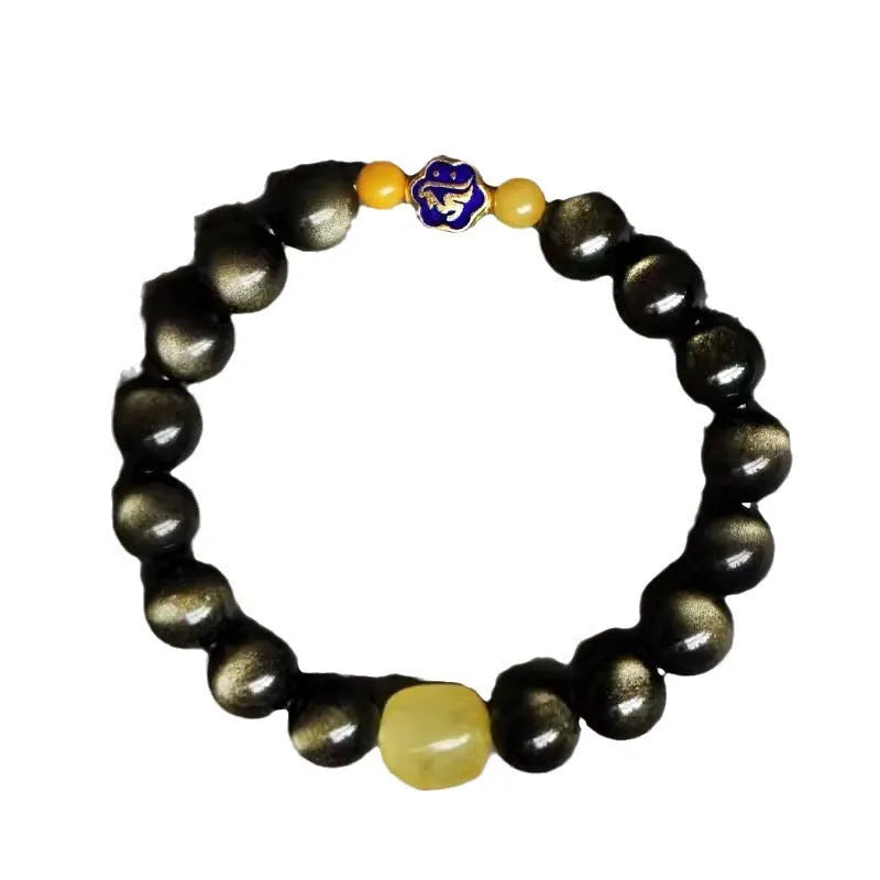 Golden obsidian bracelet with geometric beads and a detailed zodiac animal charm on a wrist.