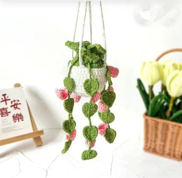 Green and white crocheted wool car plant decoration with a white hanging rope.