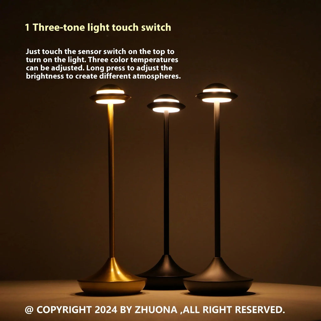 Modern UFO-shaped metal table lamp in black on a wooden desk, showing cord-free design.