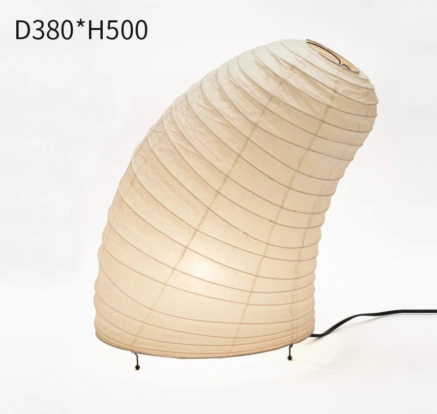Japanese style table lamp with a white handmade rice paper lantern shade and aluminium base on a wooden table.