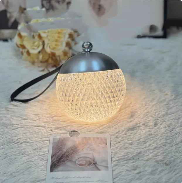 Portable cylindrical night lamp with touch control in metallic finish on wooden table