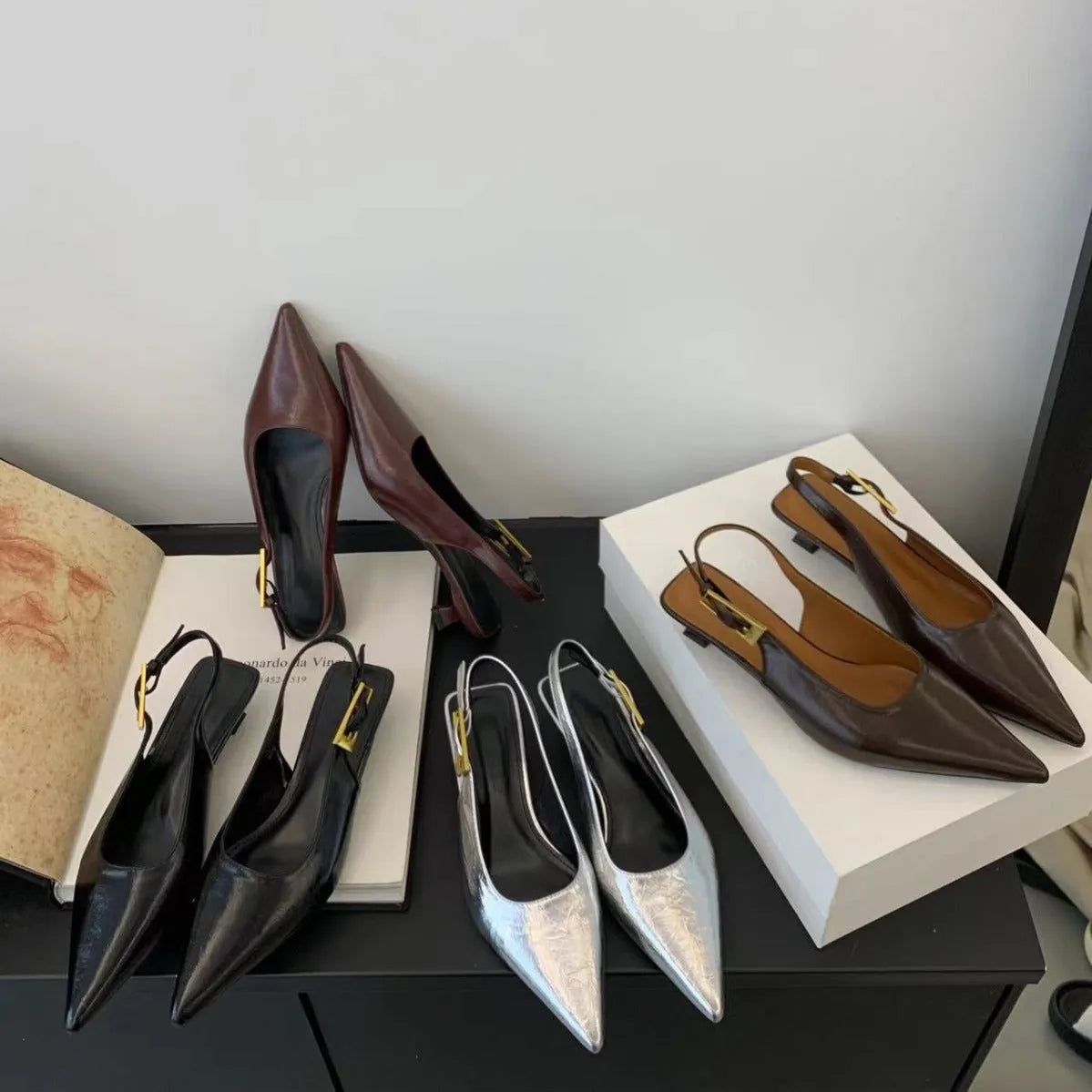 Black leather pointed toe women's shoes with a thin low heel and an ankle strap.