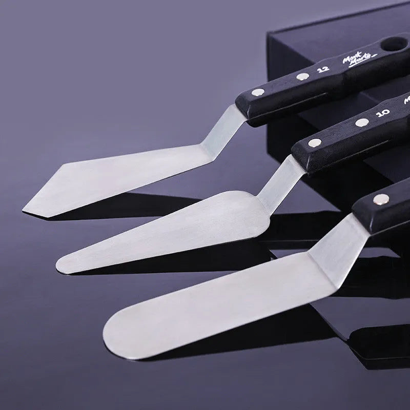 Set of three stainless steel artist palette knives numbered 3, 10, and 12 on a surface.