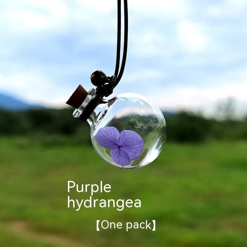 Glass car perfume pendant with preserved flowers inside, shown in a selection of different floral colours.