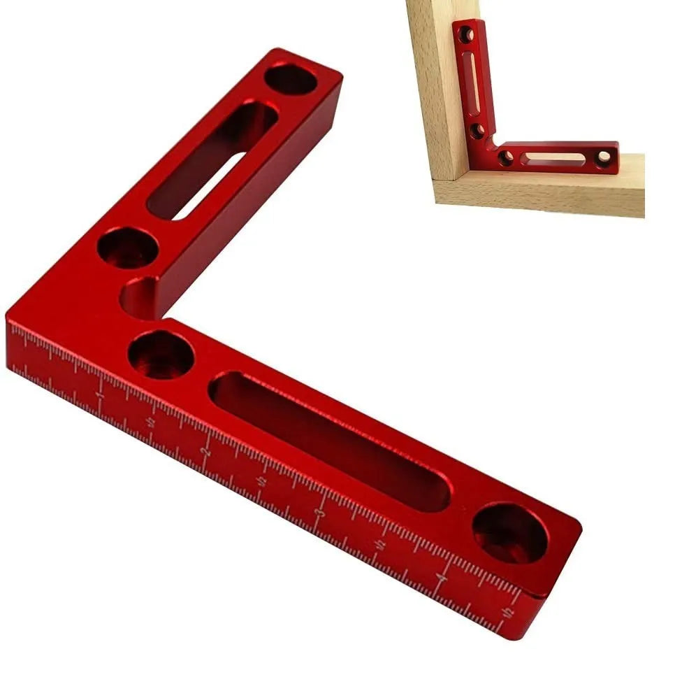 Silver aluminium right angle block clamped to a wooden workbench next to a jigsaw, showing scale markings.