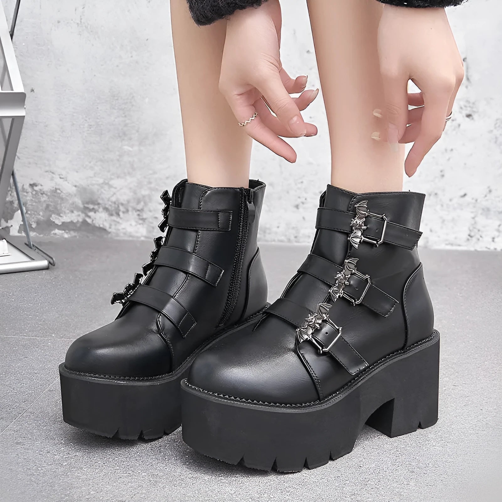 Black women's punk ankle boots with metal bat buckle and thick platform sole.