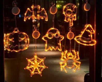Halloween battery-powered LED window lights with spider, pumpkin and ghost figures hung by suction cups.