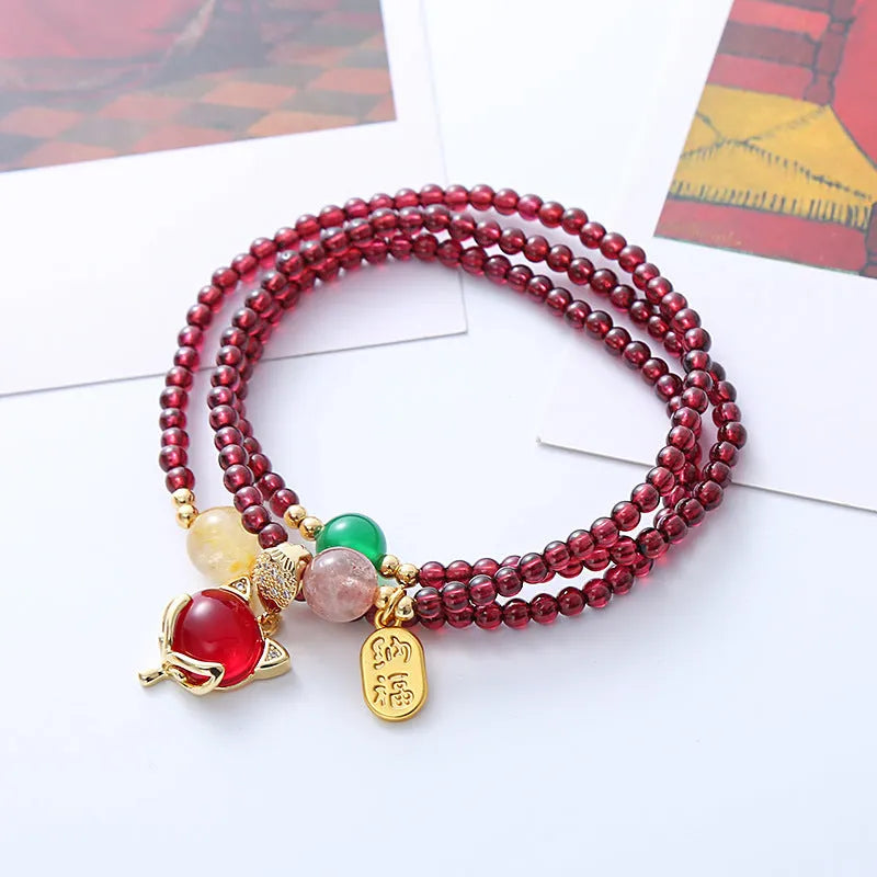 Purplish red adjustable rope bracelet with a detailed natural garnet fox charm.