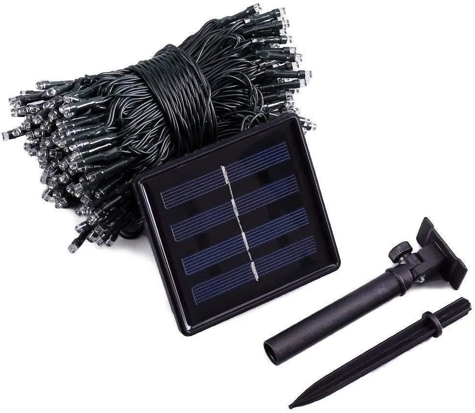 Solar-powered LED string lights with warm white bulbs on a garden fence at dusk