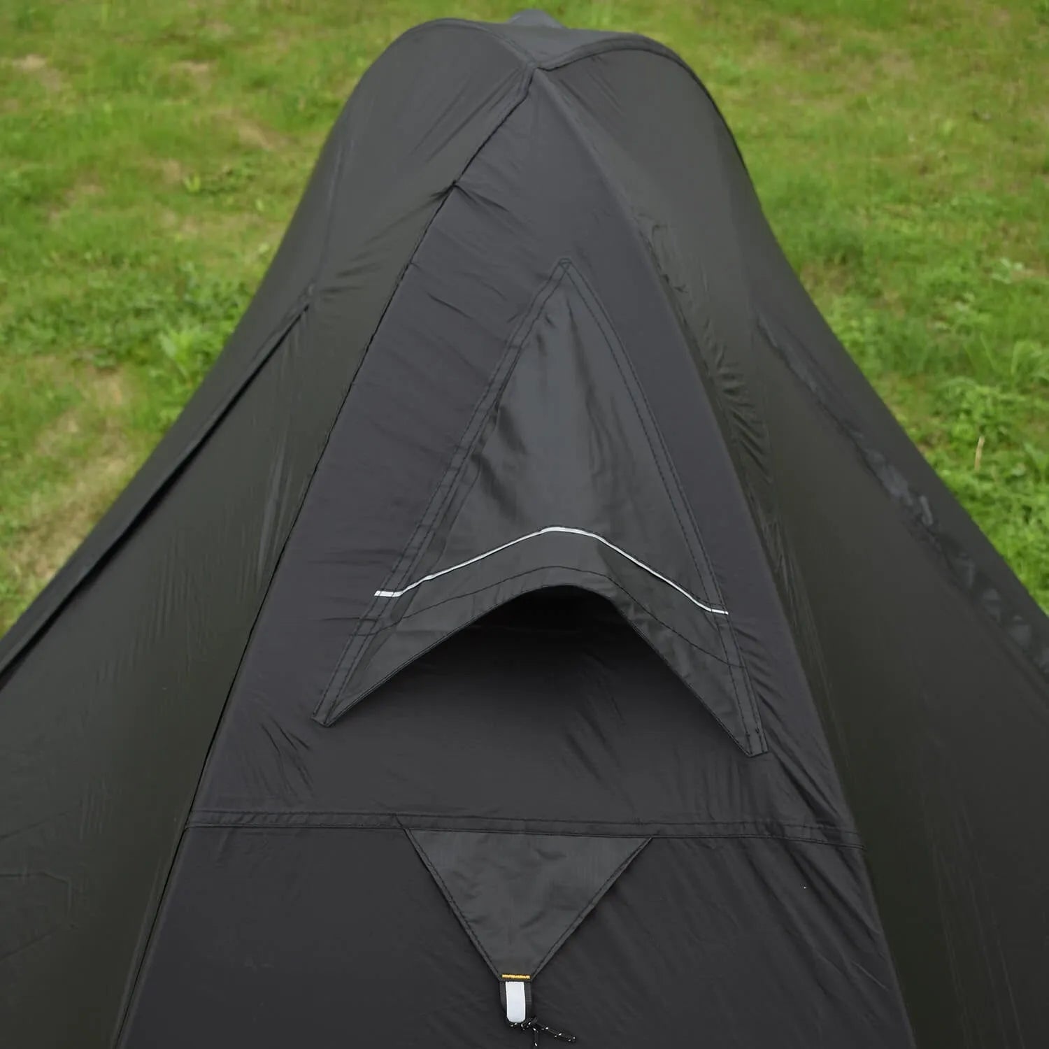 Single person orange double-layer hiking tent pitched in a field with aluminium poles visible.