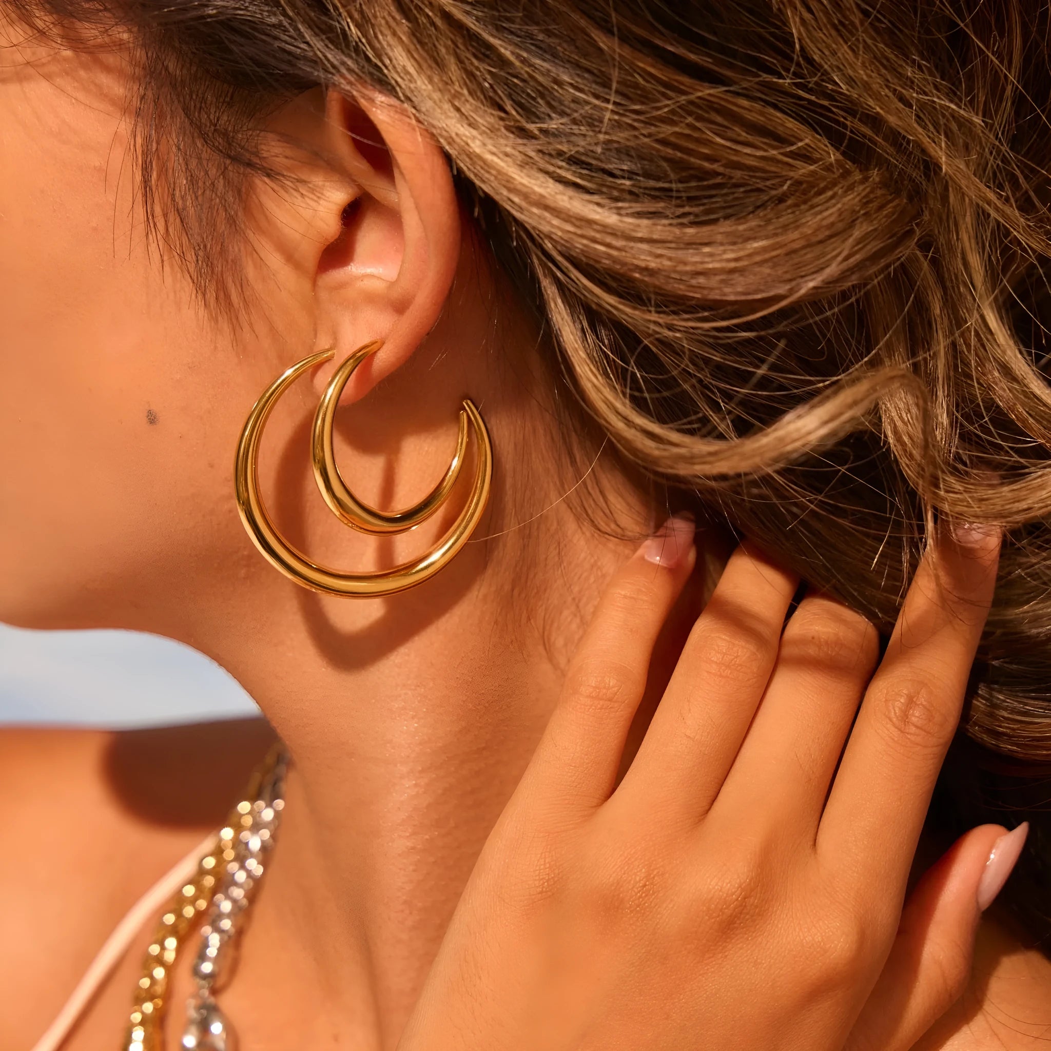 A pair of round titanium steel hoop earrings with an 18K gold plated finish, shown in large and small size options.