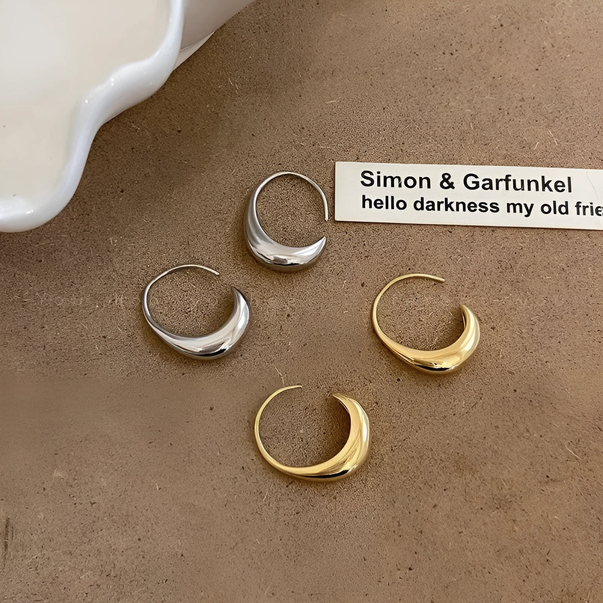 Teardrop hoop earrings in gold or silver tone alloy with C-shaped geometric design, one pair