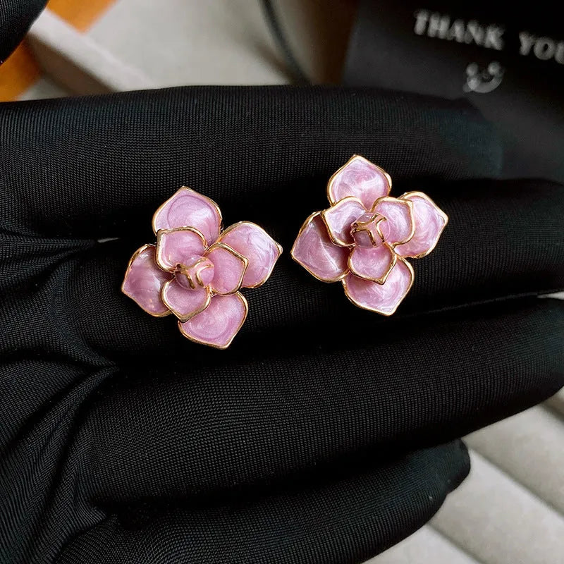 A pair of gold-plated flower stud earrings with a detailed purple oil-spot glaze finish on the petals.