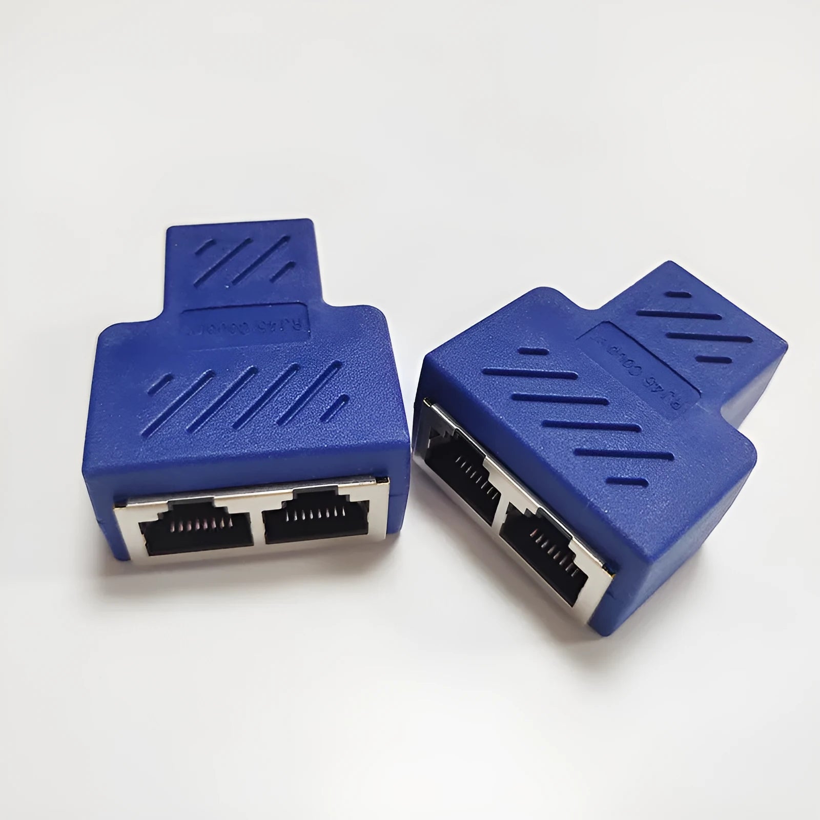 Two white RJ45 three-way tee network cable splitters on a dark surface.