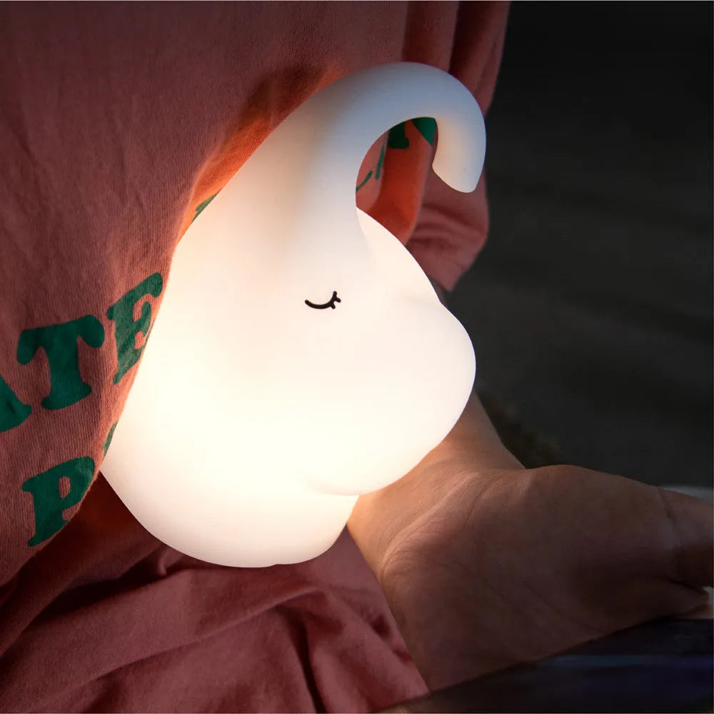 White silicone elephant-shaped night light with a warm glow on a bedside table.