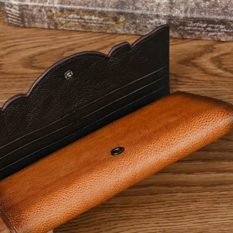 Brown tri-fold leather wallet with deep embossed floral pattern, shown open to reveal card slots and lining.
