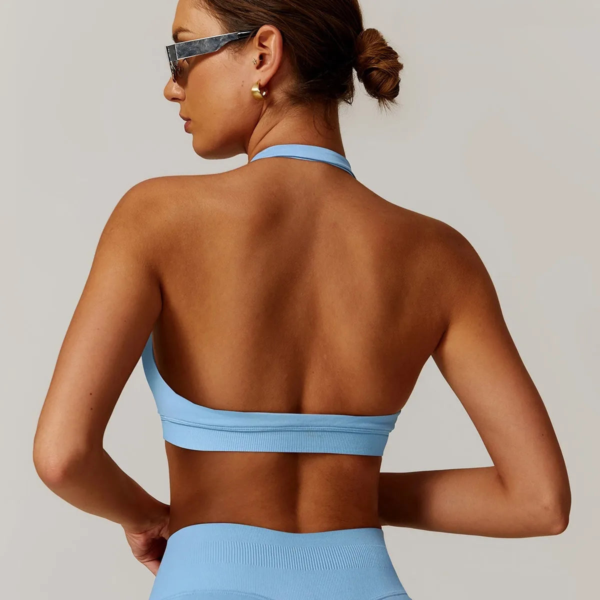 Women's black halter neck sports bra with adjustable back closure, shown from front and back.